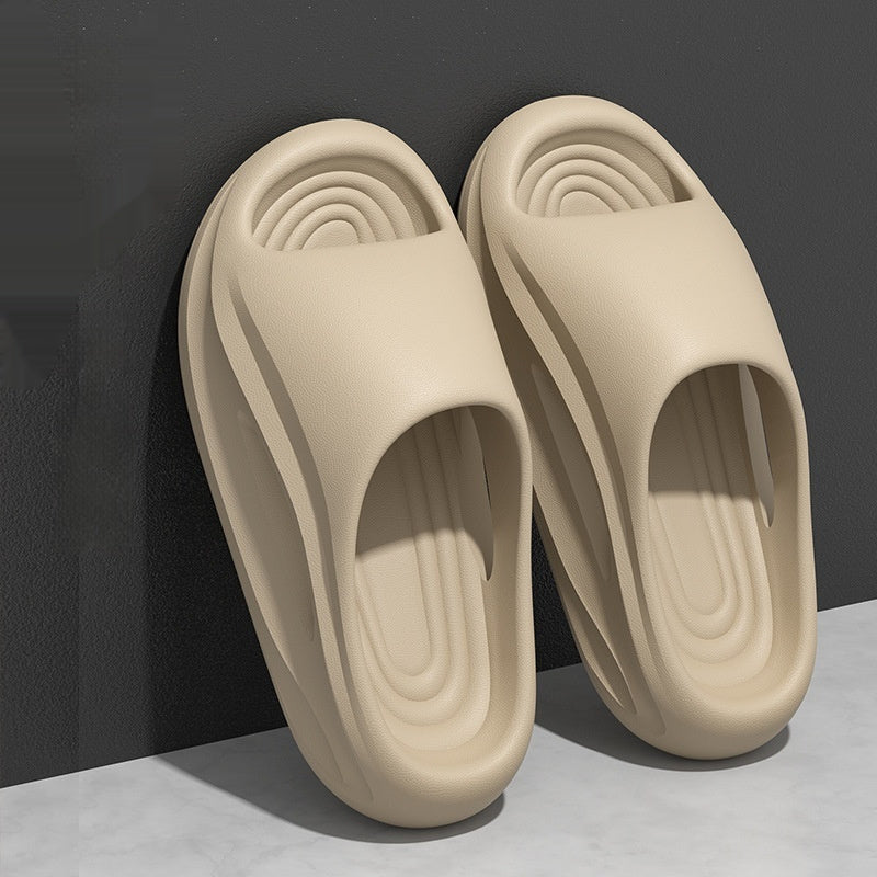 Pair of beige slippers on a gray surface with a dark background