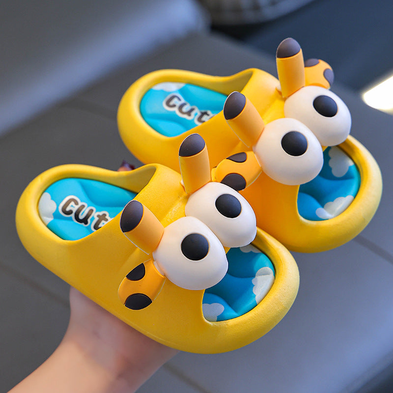 Pair of yellow butterfly-shaped sandals with blue interiors held by a hand.