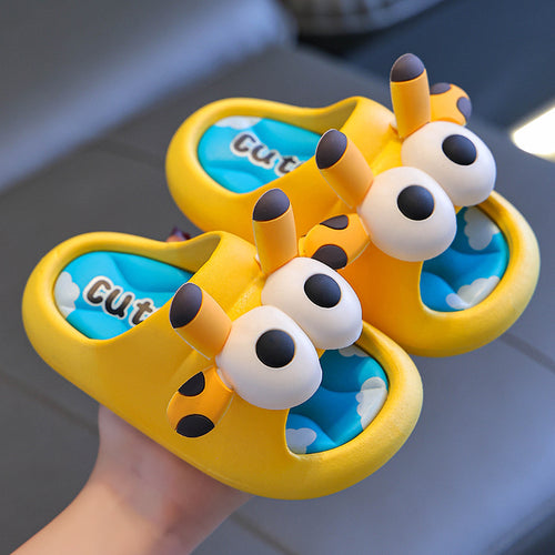 Pair of yellow butterfly-shaped sandals with blue interiors held by a hand.
