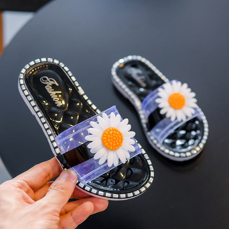 Black sandals with white flowers held by a hand on a dark surface