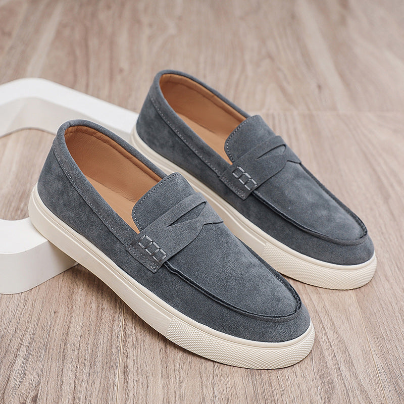 Pair of gray loafers with white soles on a wooden surface