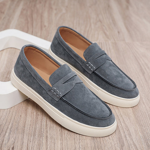 Pair of gray loafers with white soles on a wooden surface