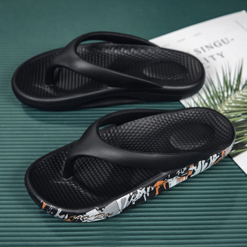Black flip-flops with floral pattern on a green surface