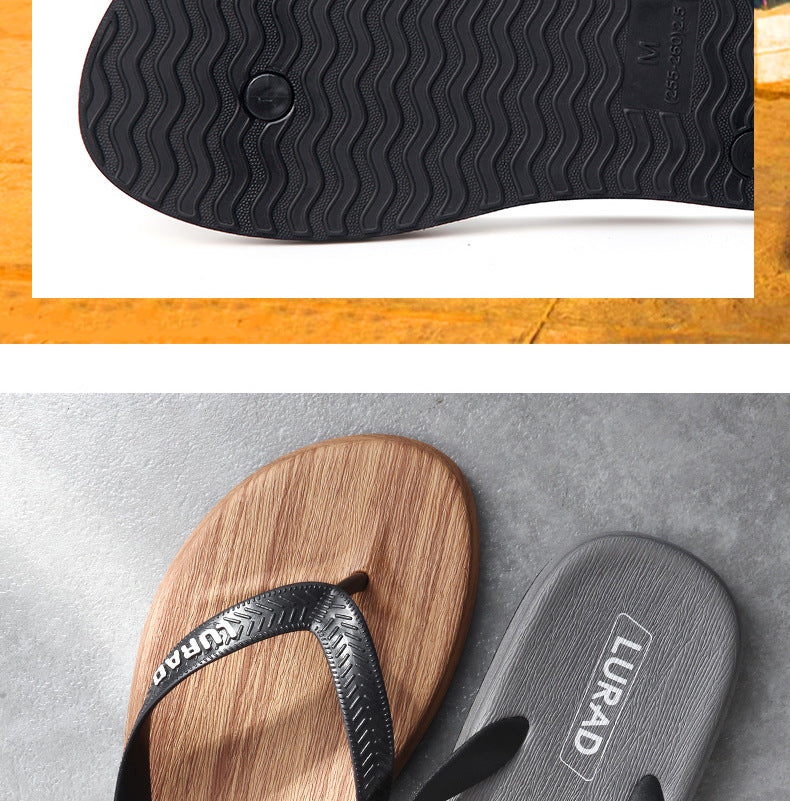 Close-up of black flip-flop sole and LURAD branded sandals on a wooden and concrete surface.