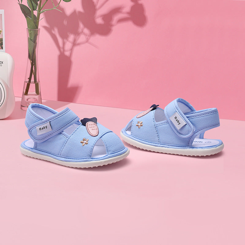 Pair of blue children's sandals on a pink surface with a pink background