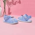 Pair of blue children's sandals on a pink surface with a pink background