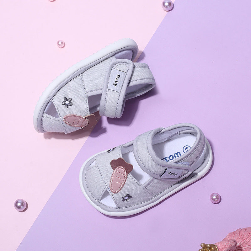 Pair of children's sandals with decorative elements on a pink background