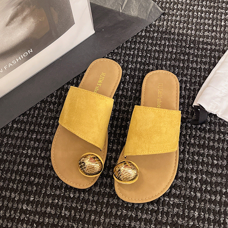 Yellow sandals with gold accents on a textured black surface