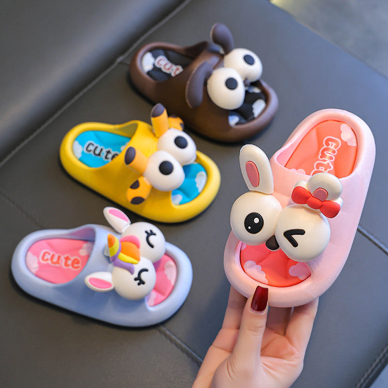 Four cartoon-style slippers with animal faces on a gray surface, one held by a hand.