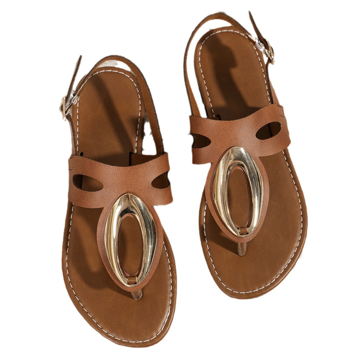 Pair of brown sandals with metallic oval accents on a white background