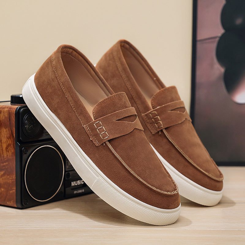 Brown loafers with white soles on a wooden surface