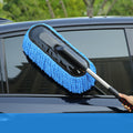 Car cleaning brush with blue microfiber head being used on a car window