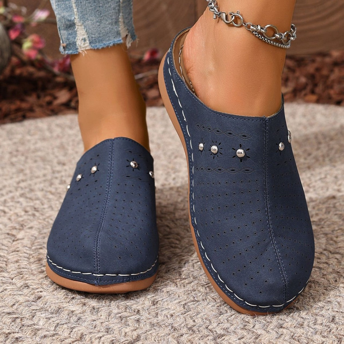 Navy blue clogs with decorative studs on a textured surface