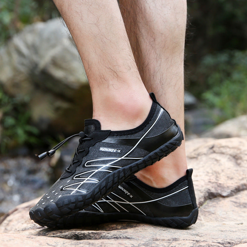 Black athletic shoes worn on a rocky surface with a natural background