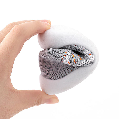 Hand holding a white spherical device with gray and white socks inside on a white background