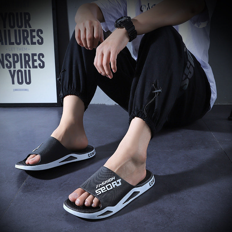 Person wearing black slides with white text on a dark floor.