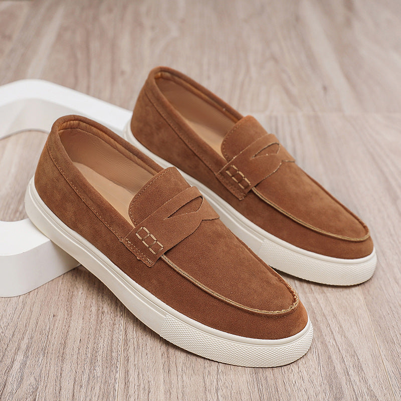 Pair of brown loafers with white soles on a wooden floor.