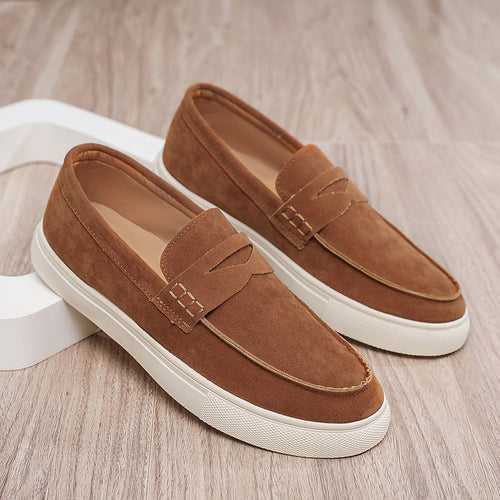 Pair of brown loafers with white soles on a wooden floor.