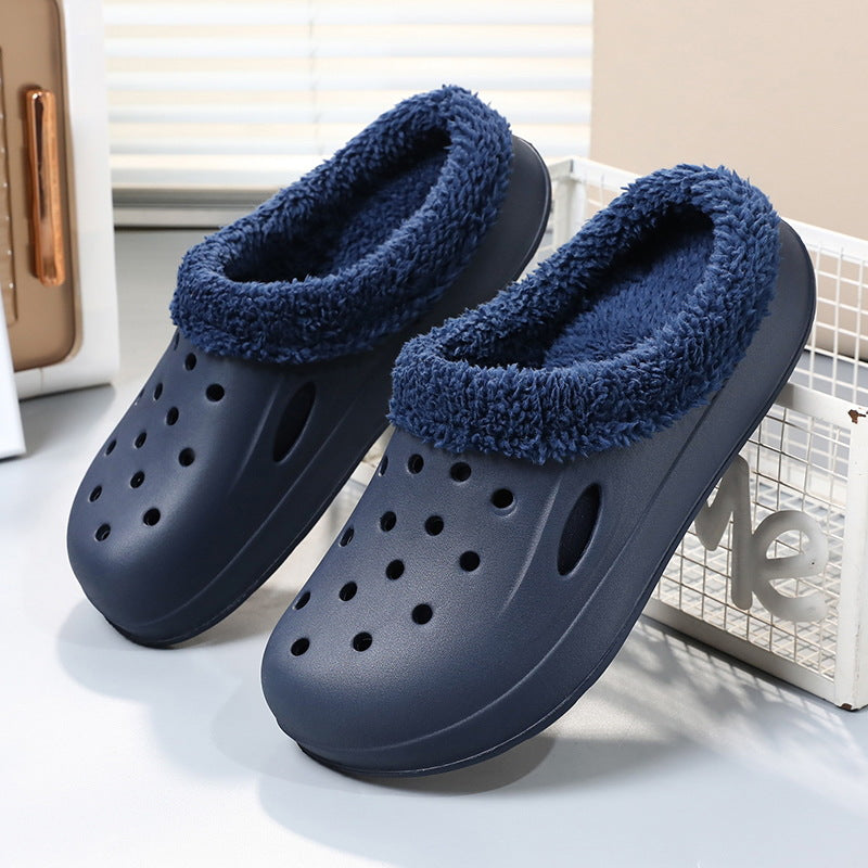 Pair of navy blue slippers with fuzzy lining on a light background