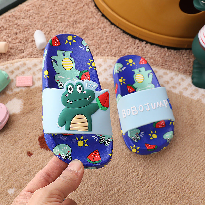 Colorful children's sandals with a cartoon design on a carpeted floor.