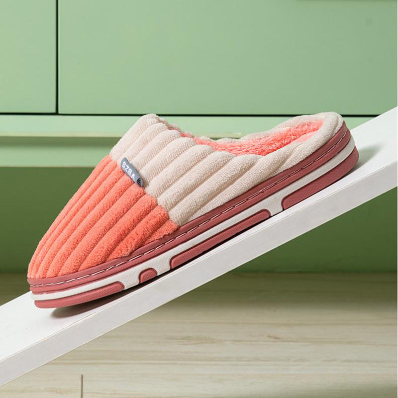 Pink and beige slipper on a white surface with a green cabinet in the background