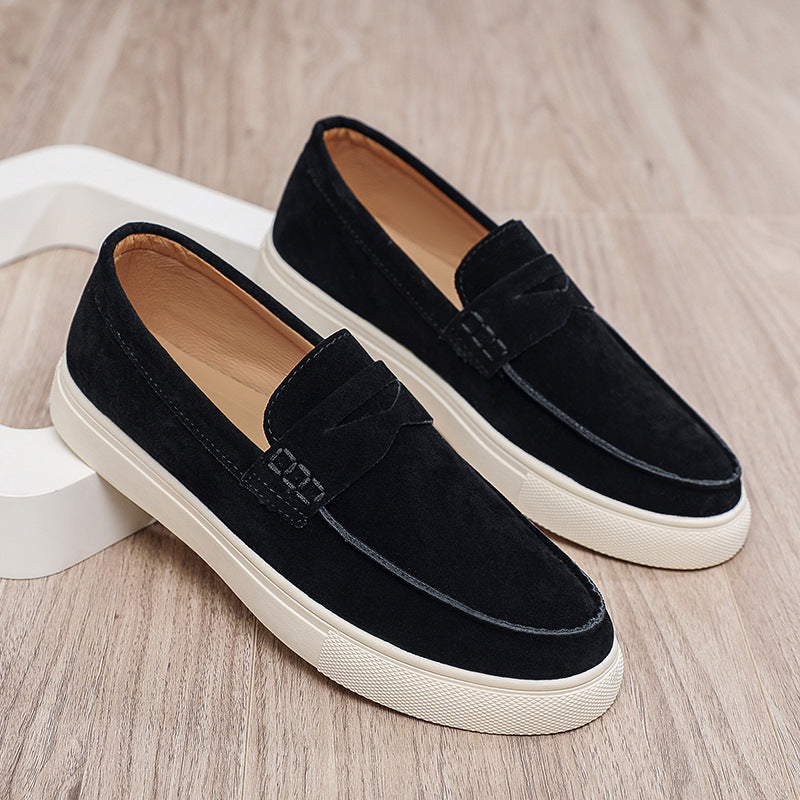 Black loafers with white soles on a wooden surface