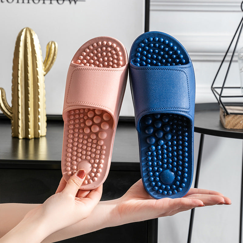 Pink and blue massage slippers held by a hand with a blurred indoor background