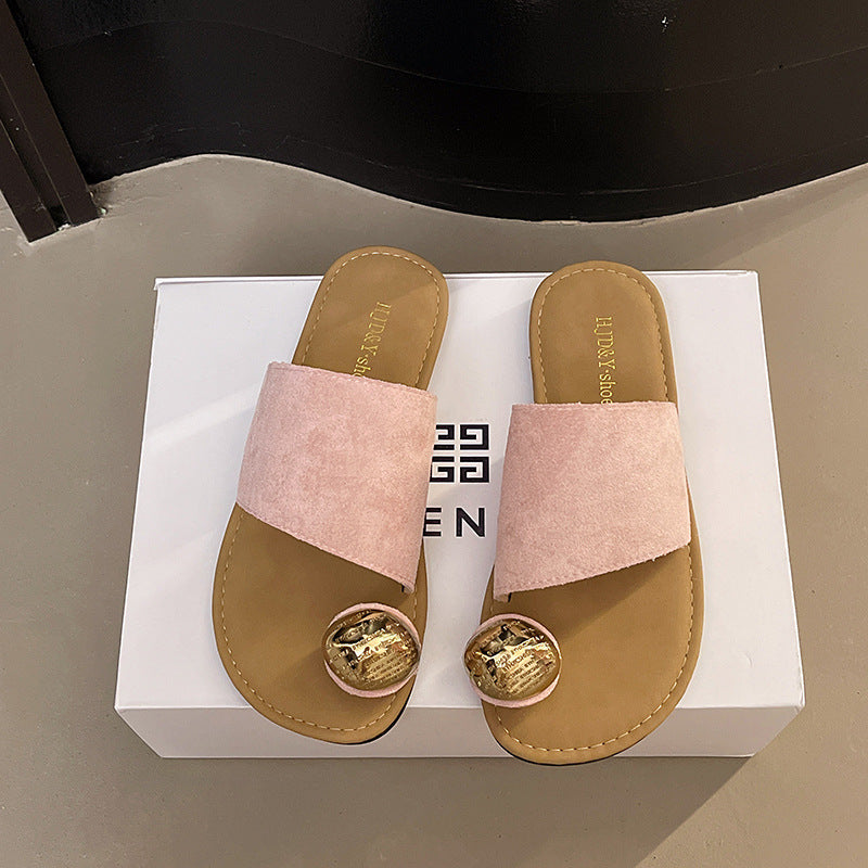Pair of pink sandals with gold accents on a white box