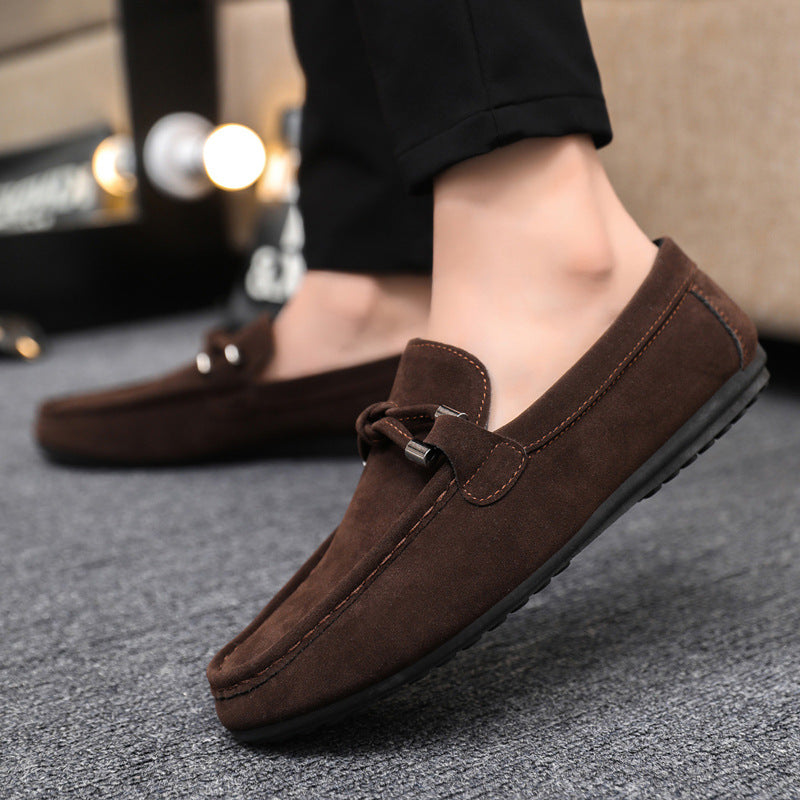 Brown loafers worn by a person on a gray surface with blurred background