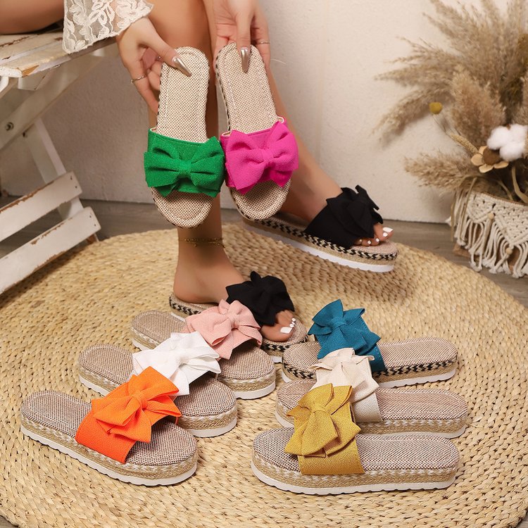 Colorful bow sandals on a woven mat with a neutral background