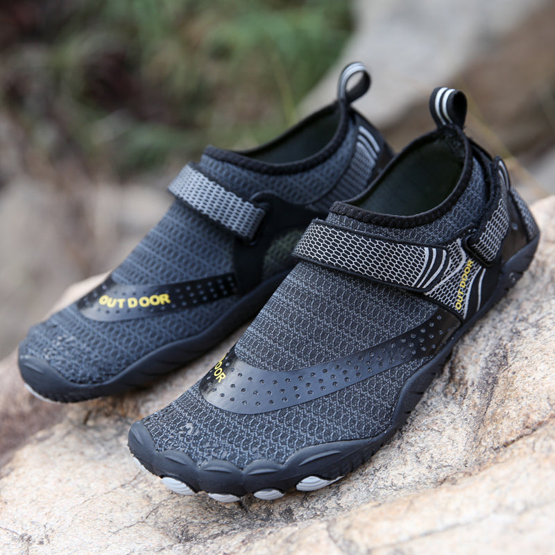 Pair of gray water shoes with text on a rock surface