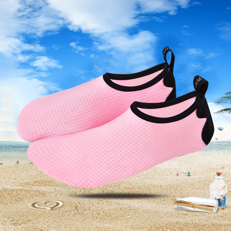 Pink water shoes with black straps on a beach background
