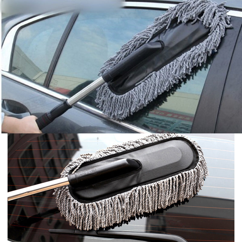 Car cleaning brush with extended handle on a car window, close-up view.
