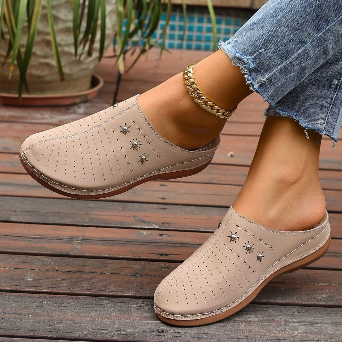 Beige clogs with star patterns worn by a person on a wooden floor.
