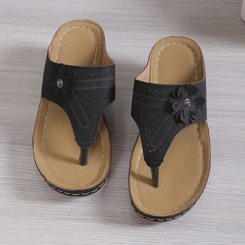 Pair of black sandals with floral design on a gray surface