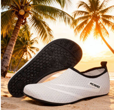 White water shoes with black soles on a beach with palm trees and sunset in the background
