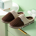 Pair of brown and beige slippers on a green surface with a light green background.