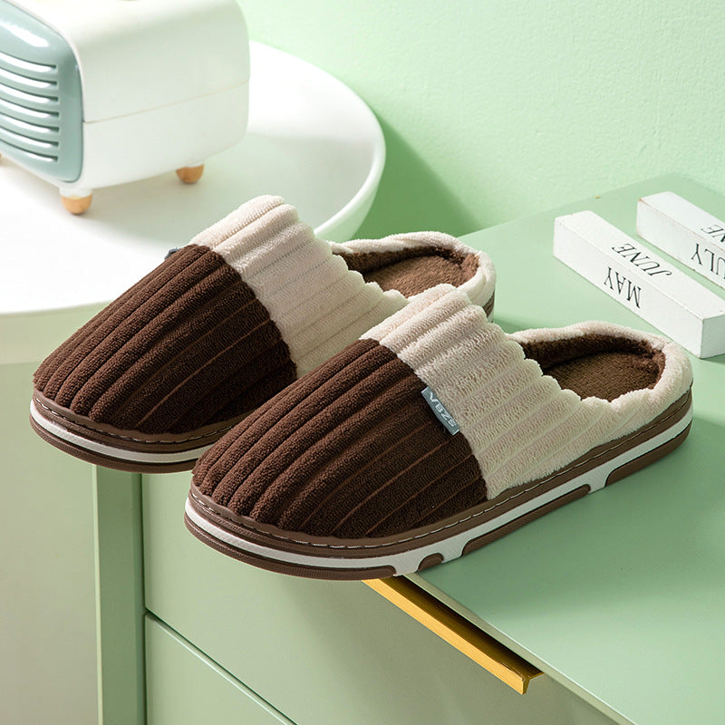 Pair of brown and beige slippers on a green surface with a light green background.