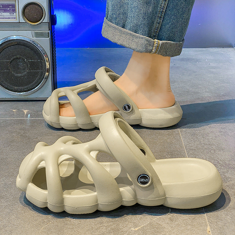 Beige sandals with a brand logo worn by a person on a tiled floor.