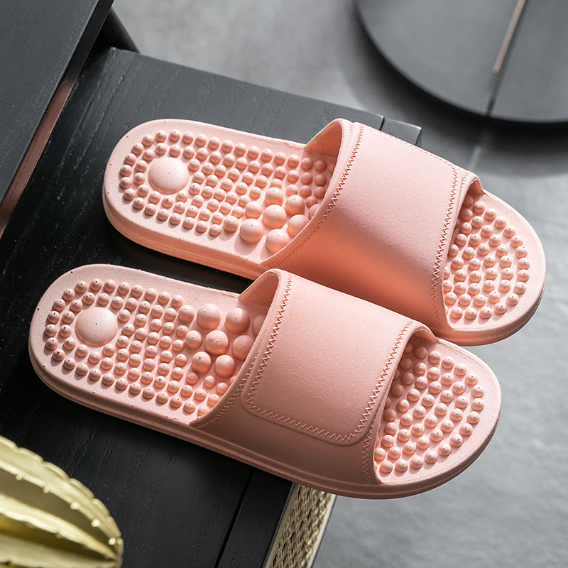 Pair of pink slippers with textured sole on a dark surface