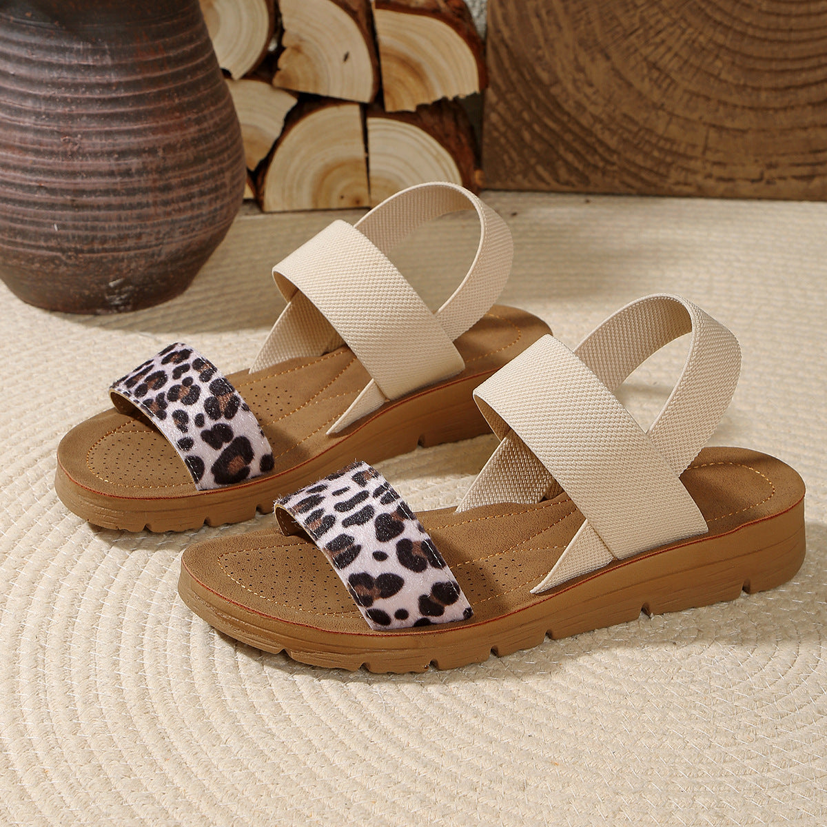 Pair of sandals with leopard print straps on a textured surface.