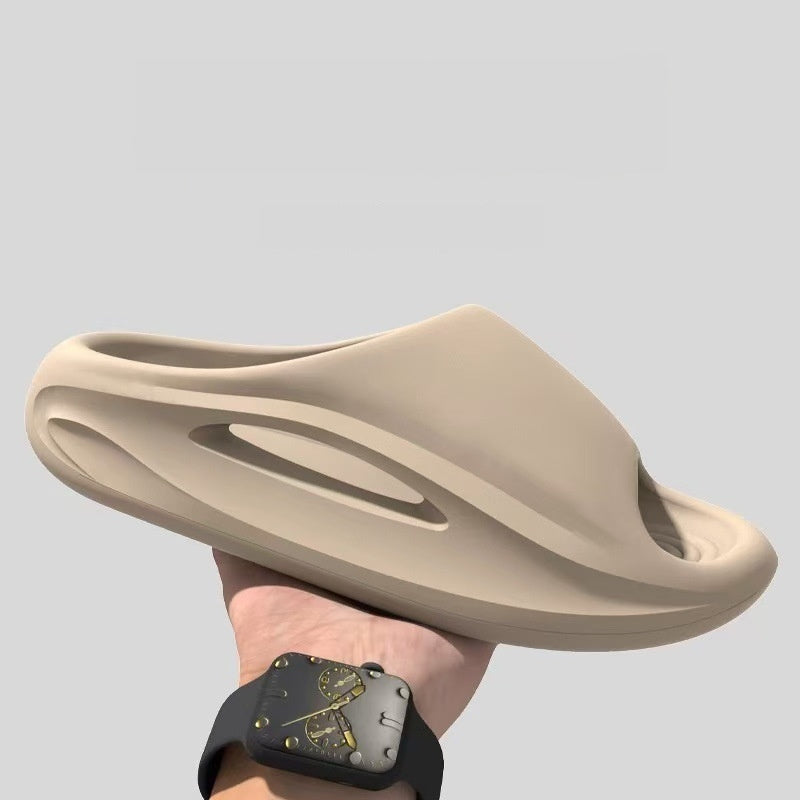 Beige sandal held by a hand against a light gray background