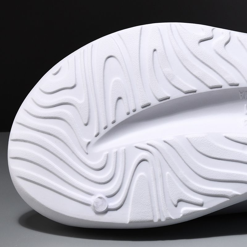 Close-up of a white shoe sole with wavy pattern on a black background