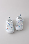 Pair of white baby shoes with colorful patterns on a light gray background