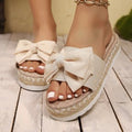 Beige sandals with bow details on a wooden floor