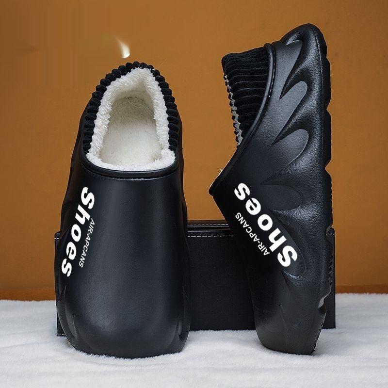 Black clogs with white interior and 'Shoes' branding on a white surface with brown background