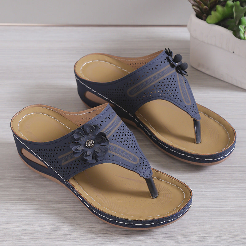 Pair of blue sandals with floral designs on a light wooden surface.