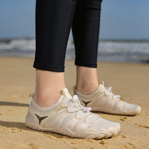 White sneakers on a sandy beach with a blurred ocean background