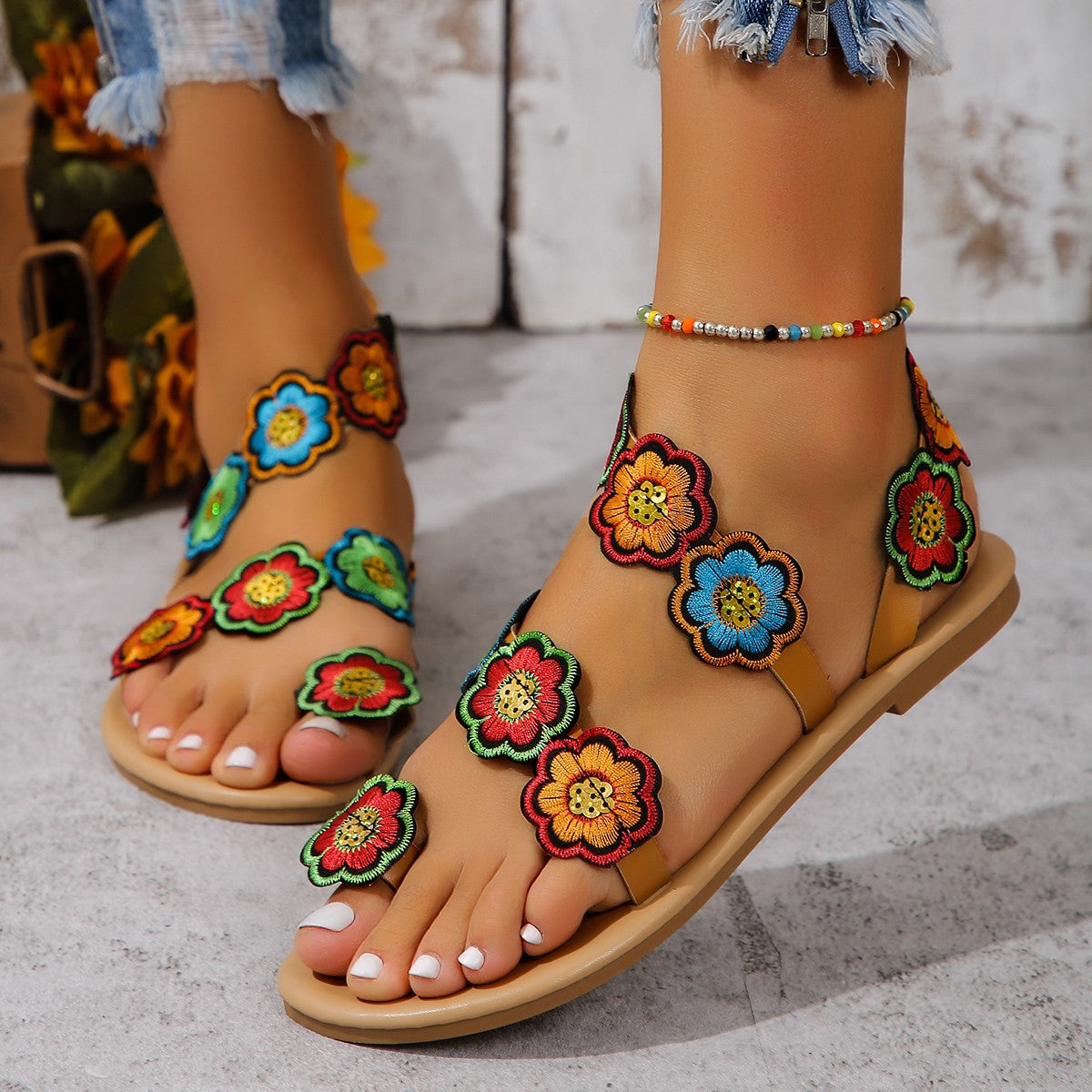 Colorful floral sandals worn with a denim skirt on a light background