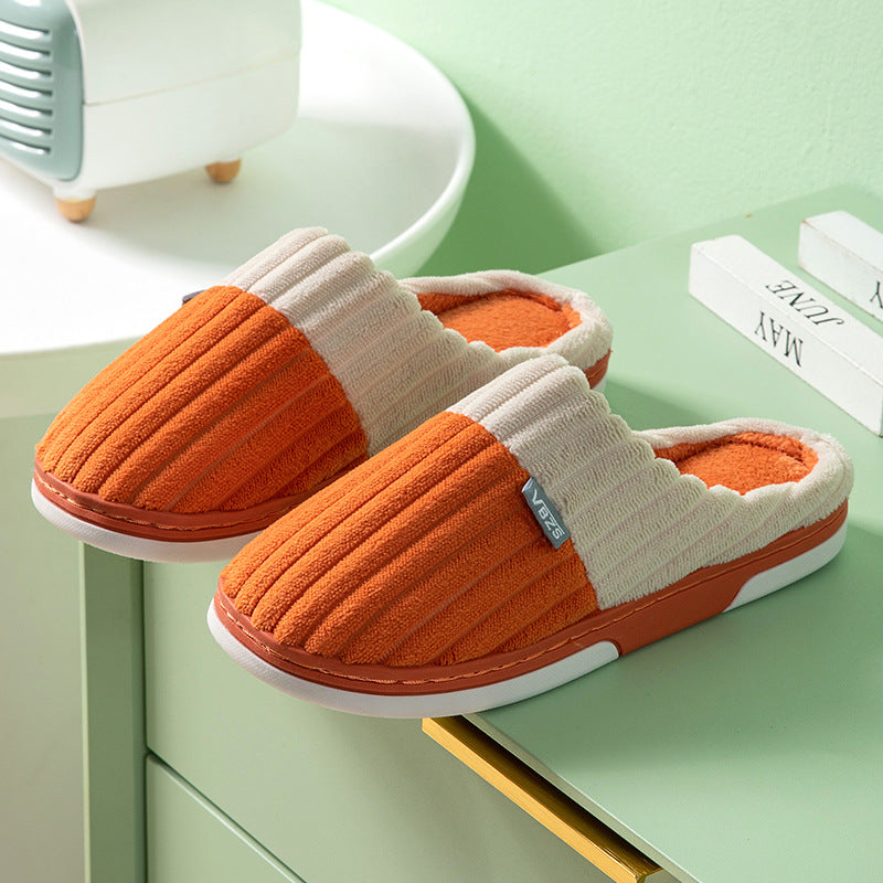 Pair of orange and beige slippers on a green surface